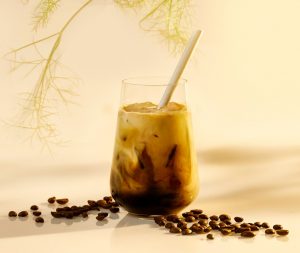 glass of iced latte with straw and coffee beans