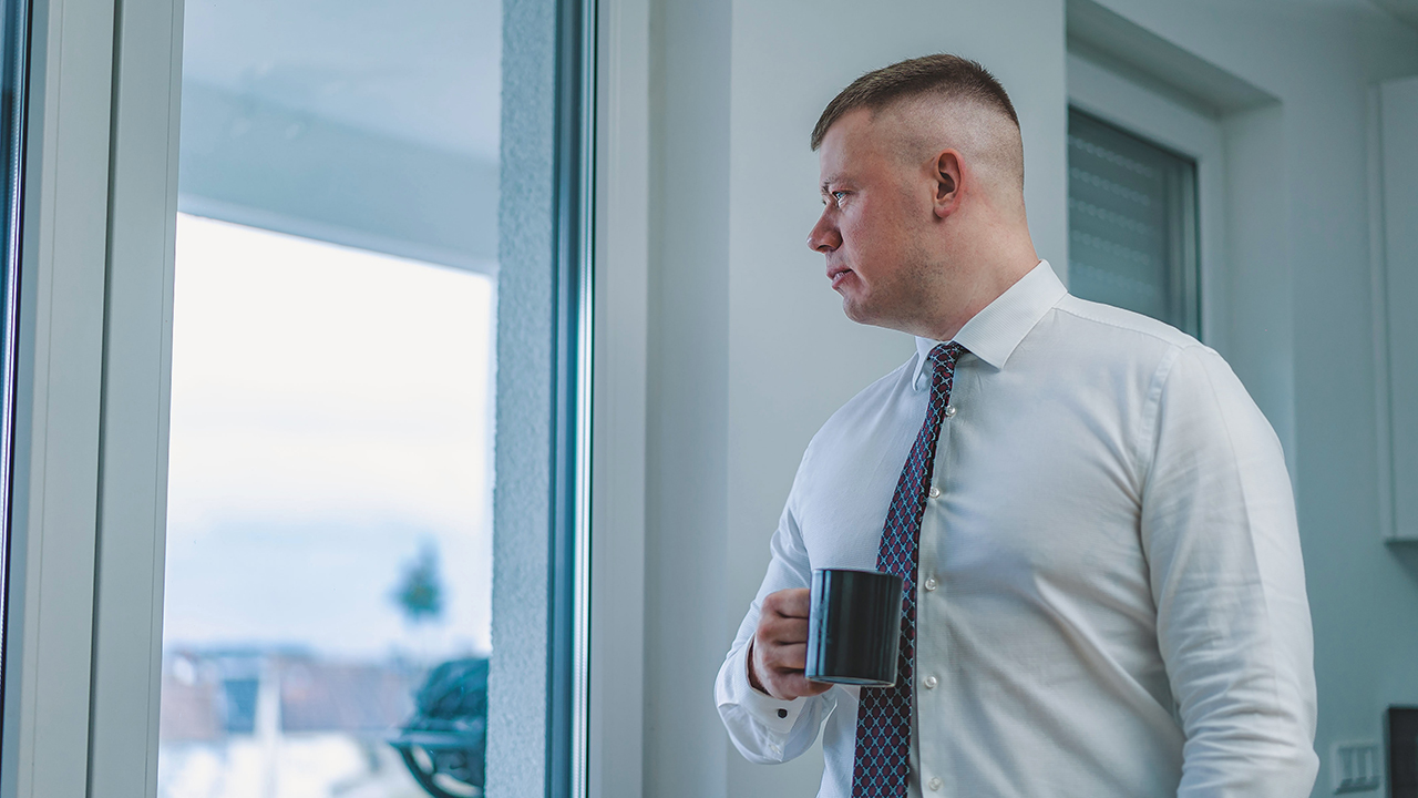 mindfulness at work (man looking out window holding coffee)