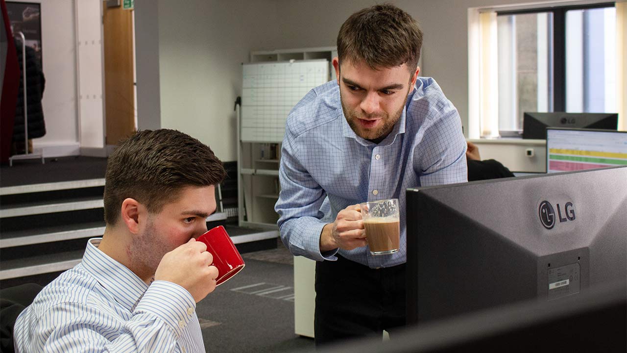 two men drinking coffee in an office