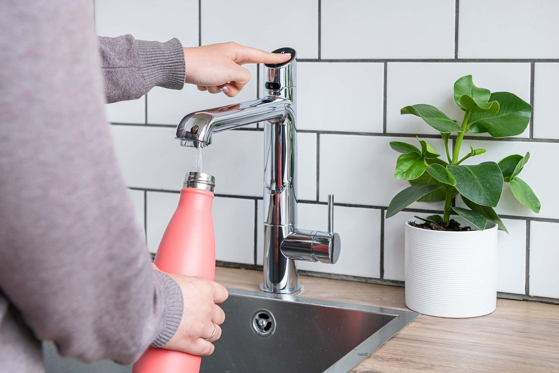 person filling a pink water bottle at a Zip tap